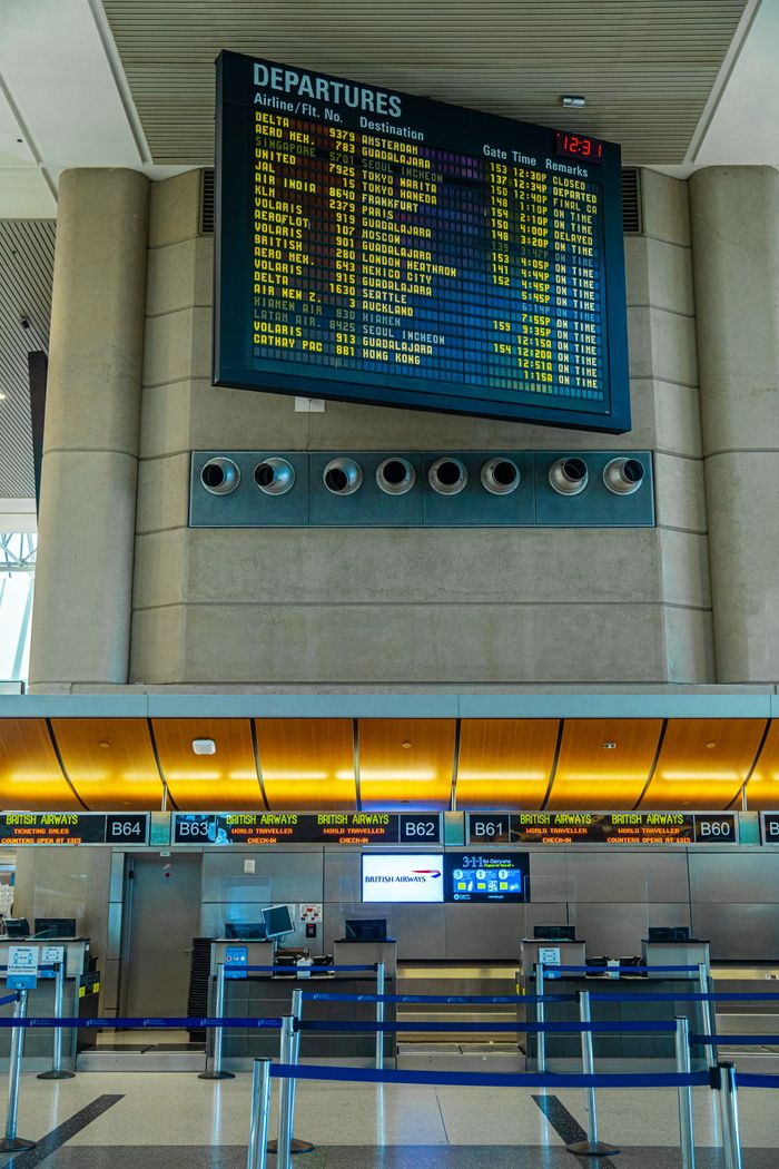 Digital departure board and airline check-in counters inside a modern airport terminal.