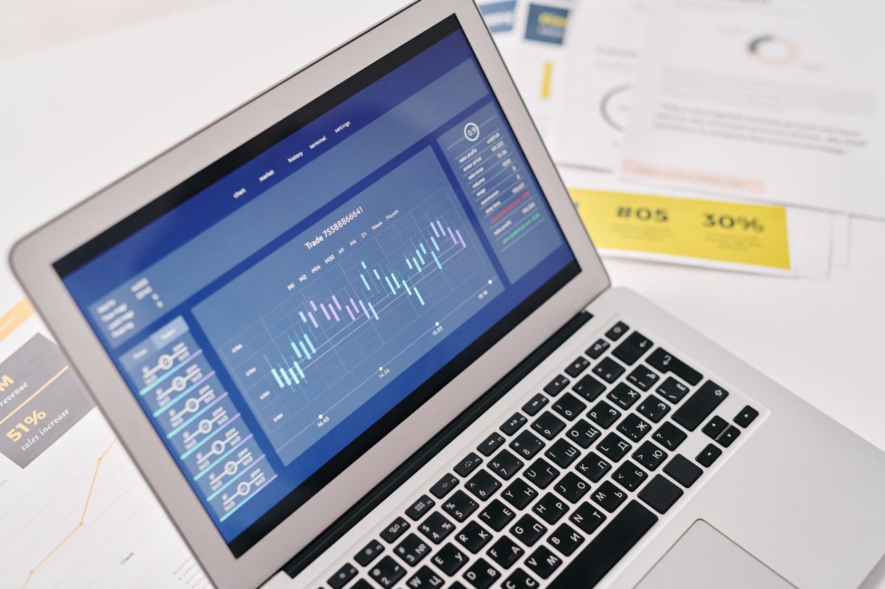 Open laptop displaying financial graphs and analytics with documents nearby, ideal for business presentations.